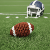 Crocheted football on a grass field with a helmet in the background