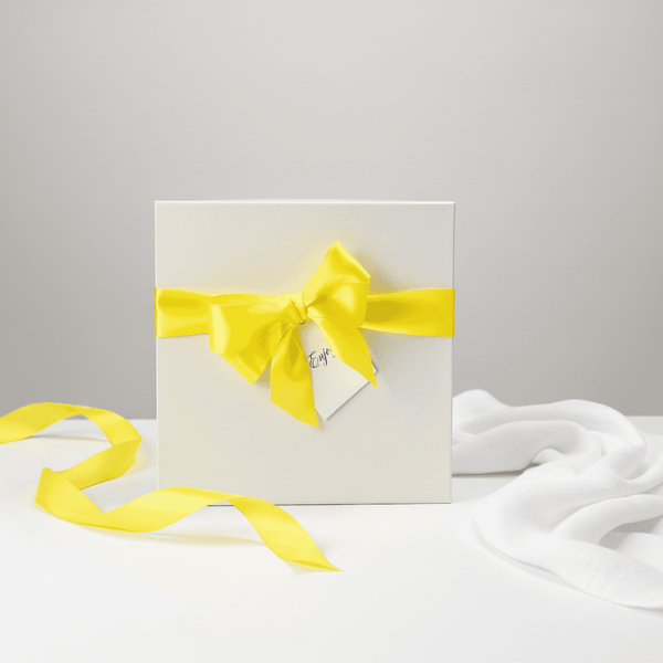 White gift box with a yellow ribbon on a light gray background