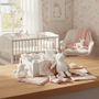 Baby items including a unicorn plush toy, baby clothes, and blankets on a table in a nursery