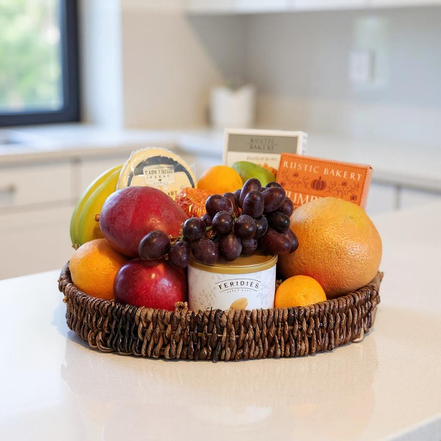 Fruit basket with apples, oranges, and grapes on a kitchen counter.