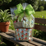 Gift basket with floral garden bag and green bow on a wooden bench outdoors