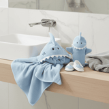 Blue shark-themed towel and plush bath mitt and booties on a bathroom counter