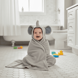 Baby wrapped in a gray elephant-themed towel in a bathroom