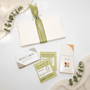 Collection of self-care items including cards, tea packages, and a box on a white surface with greenery