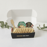 Crackerology Red Wine and Rosemary Snackable open box with crackers, cheese, and a spatula on a white background