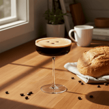 Glass of craftmix espresso martini on a wooden table with bread and coffee beans.