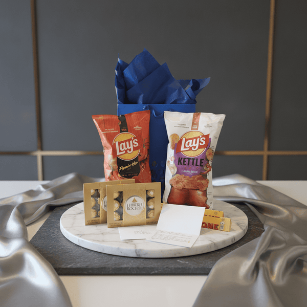 Blue gift bag with crinkled paper, Lay's snack packs and note cards on tray
