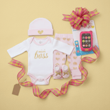 Baby clothing set with 'mini boss' onesie, pink hat, and baby shoes on a yellow background