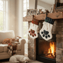 Two plaid stockings with paw prints hanging above a fireplace in a cozy living room