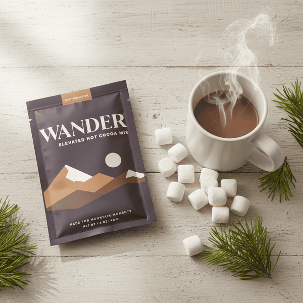 Wander Hot Cocoa packet, steaming mug, and mini marshmallows on a rustic tabletop, perfect for gifting or adventures with Celebratopia's curated offerings.