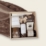 Gift set with items including a gingerbread mug, socks, candle and snacks in a wooden box.