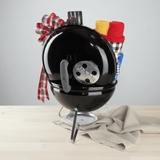 Black barbecue grill with decorative items on a light surface
